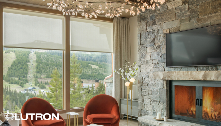 Elegant living room with Lutron motorized shades partially lowered over large windows, showcasing a scenic mountain view.